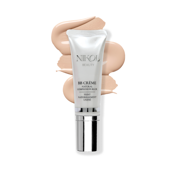 A sleek tube of Nikol Beautys BB CRÈME, in silver and white, featuring hyaluronic acid and the Natural Complexion Blur label, stands in front of a swirl of beige cream that hints at its texture and color.