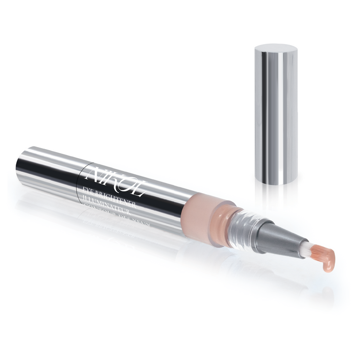 The Nikol Beauty Eye Brightener is a sleek, silver pen-style applicator with a transparent section revealing the nude-tone product. Remove the cap to uncover the brush tip coated with brightener, enhanced with Chamomile Flower Water for gentle application.