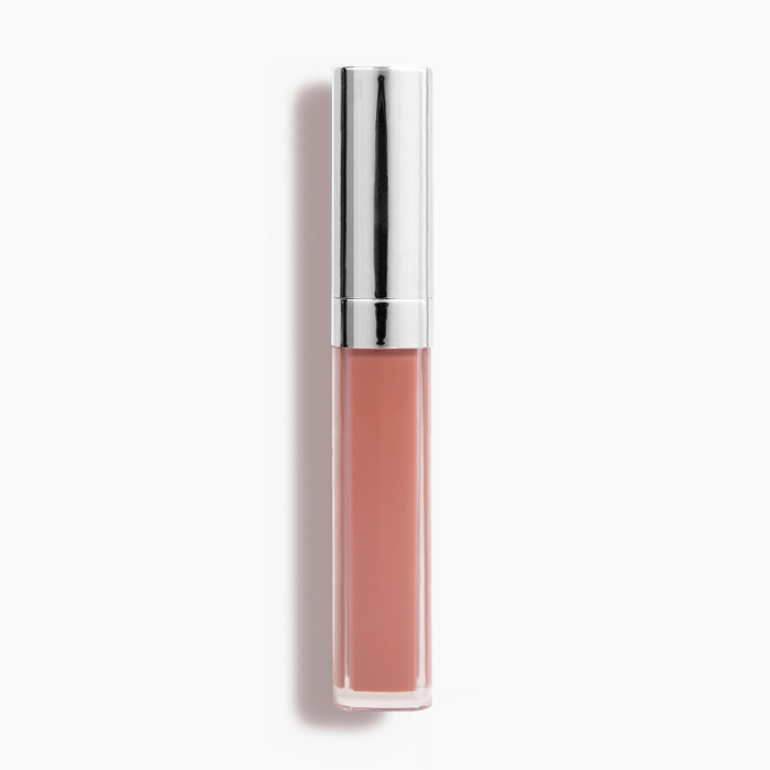 The Good Vibes Lip Gloss #443 by Nikol Beauty, in a nude shade with high-impact shine and a metallic silver cap, stands upright against a plain white backdrop.