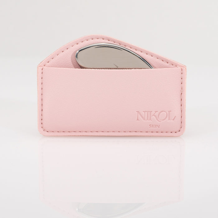 A pink leather pouch embossed with Nikol Beauty holds the Gua Sha Stainless Steel tool, partially visible inside and ideal for lymphatic drainage, set against a white background.