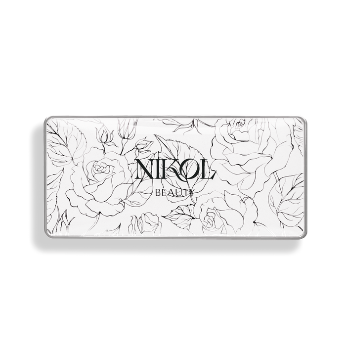 A white rectangular box with Nikol Beauty encases the In Full Bloom Blush Palette. It features black line drawings of roses and leaves against a black background, promising a luminous finish from its natural ingredients.