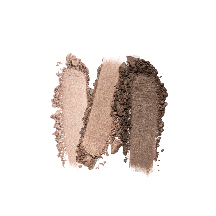 Three overlapping swatches of brown makeup powder in light to dark shades are smeared on a white background, showcasing the texture and pigmentation of Nikol Beautys Le Bottled Blonde 3-Well Eyeshadow Palette, a clean beauty must-have with a vegan formula for a guilt-free glow.