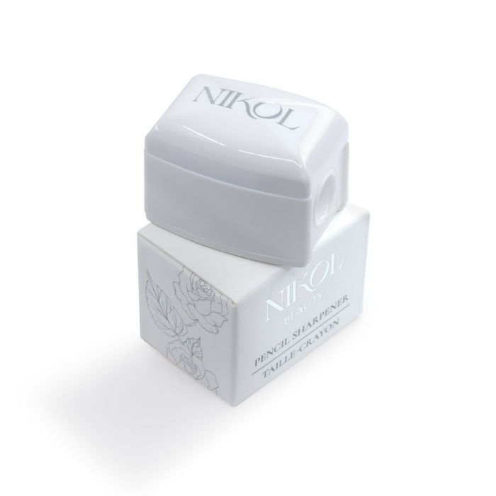 The Nikol Beauty Pencil Sharpener, an essential for any makeup bag, features a white design with silver lettering and floral patterns on its rectangular base. It has a removable top and is ideal for achieving professional eyeliner application.