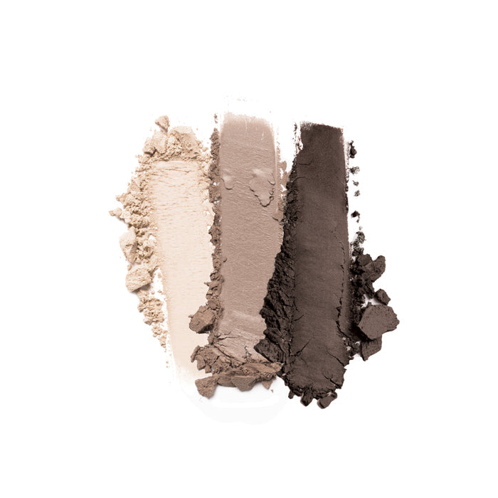 Three swatches from Nikol Beautys Rewrite The Rules 3-Well Eyeshadow Palette lie on a white background, showcasing the silky texture of the light beige, soft taupe, and dark brown matte shades side by side.