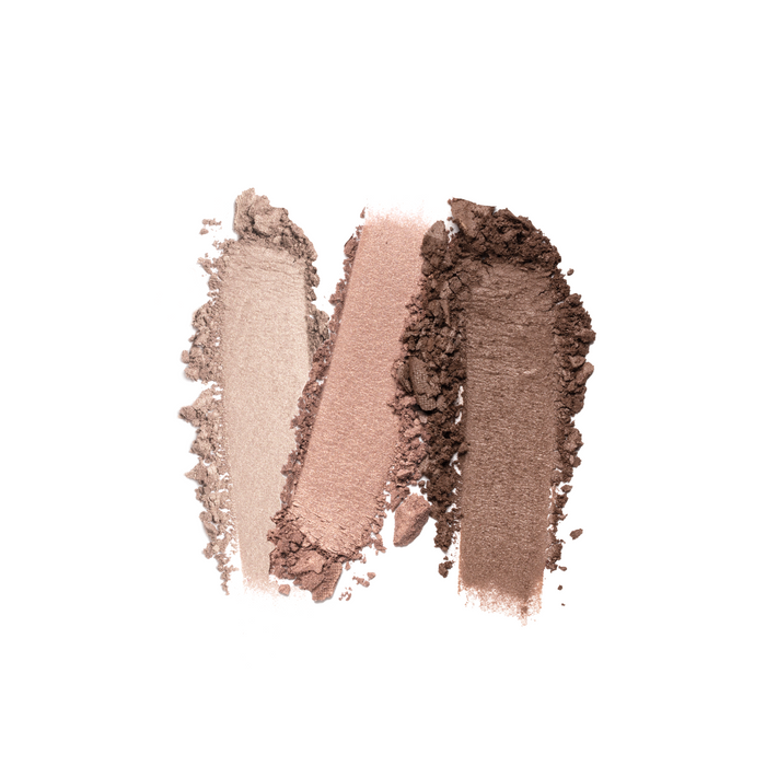 Three eyeshadow swatches in light beige, pink, and dark brown are displayed on a white background, showcasing their textured, powdery finish. Discover effortlessly stunning looks with Nikol Beautys vegan The Cabana 3-Well Eyeshadow Palette.